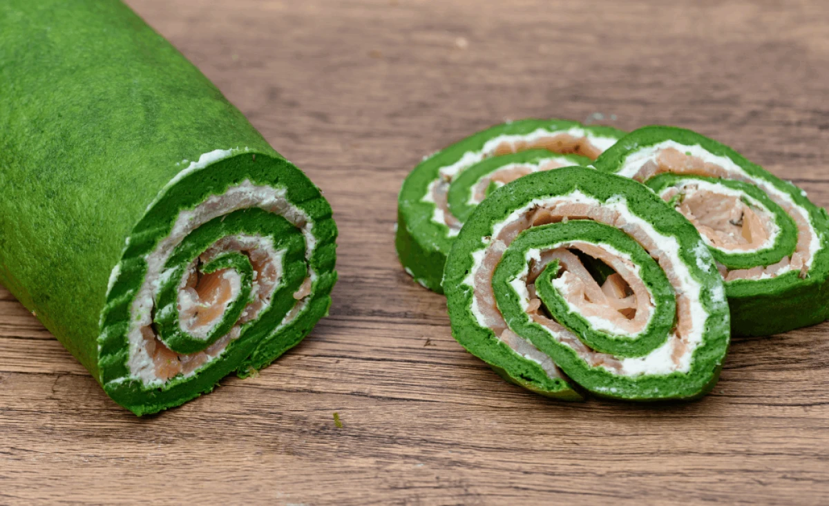 Pokrojone w plastry roladki z naleśników szpinakowych z kremowym serkiem i wędzonym łososiem